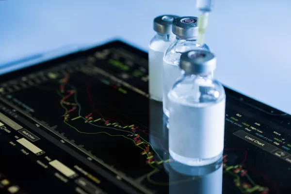 Digital generated image of syringe and bottle with Covid-19 vaccine standing on dark blue data surface.