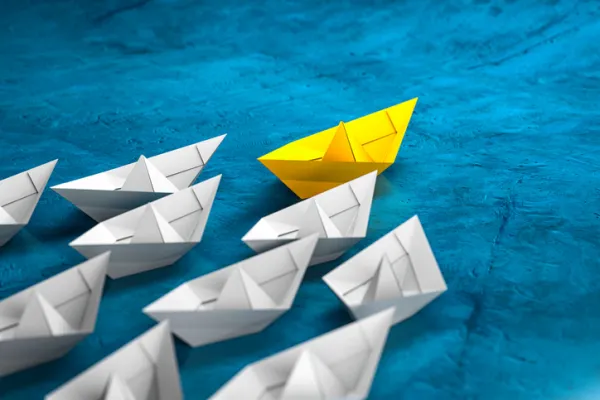 Leadership, success, and teamwork concept, yellow leader paper boat leading white followers boats. 3D Render