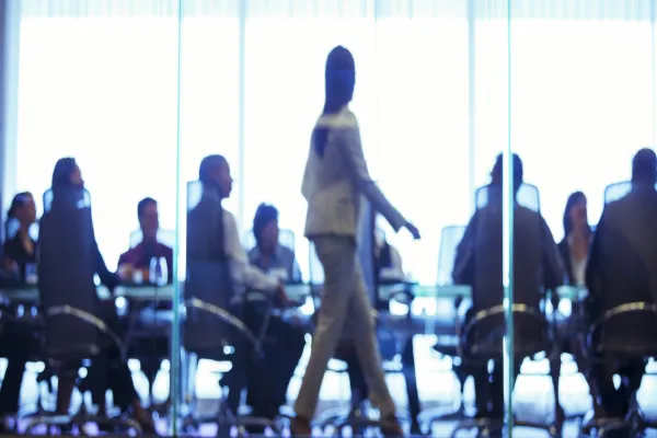 Businesswoman walking in front of colleagues during business meeting in conference room