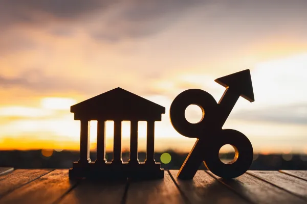 Silhouette of Bank symbol and Percentage model on wood table. Concepts of the banking system, rising interest rates, inflation, deflation, and savings.