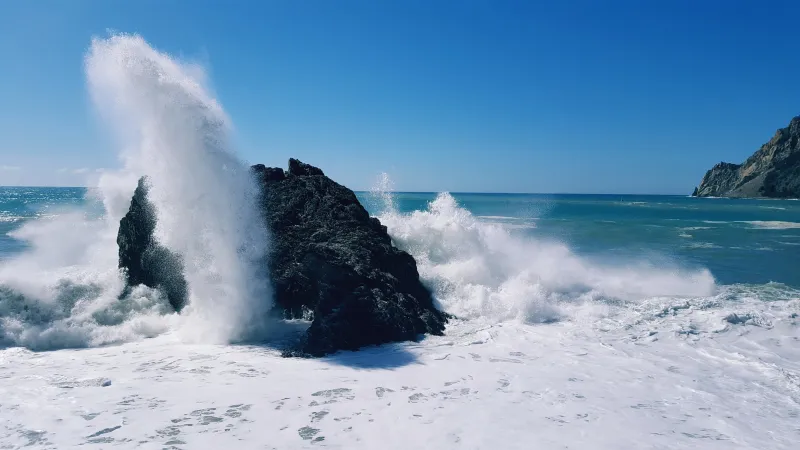 Turbulent sea and wave exploding on a rock